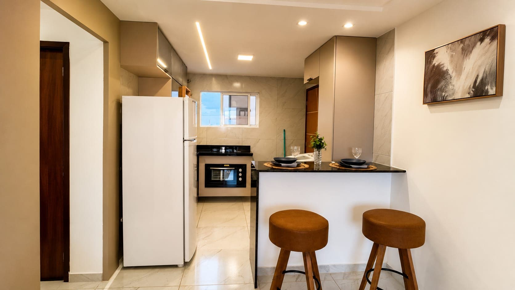 Sala e cozinha americana com bancada de granito e banquetas em unidade decorada