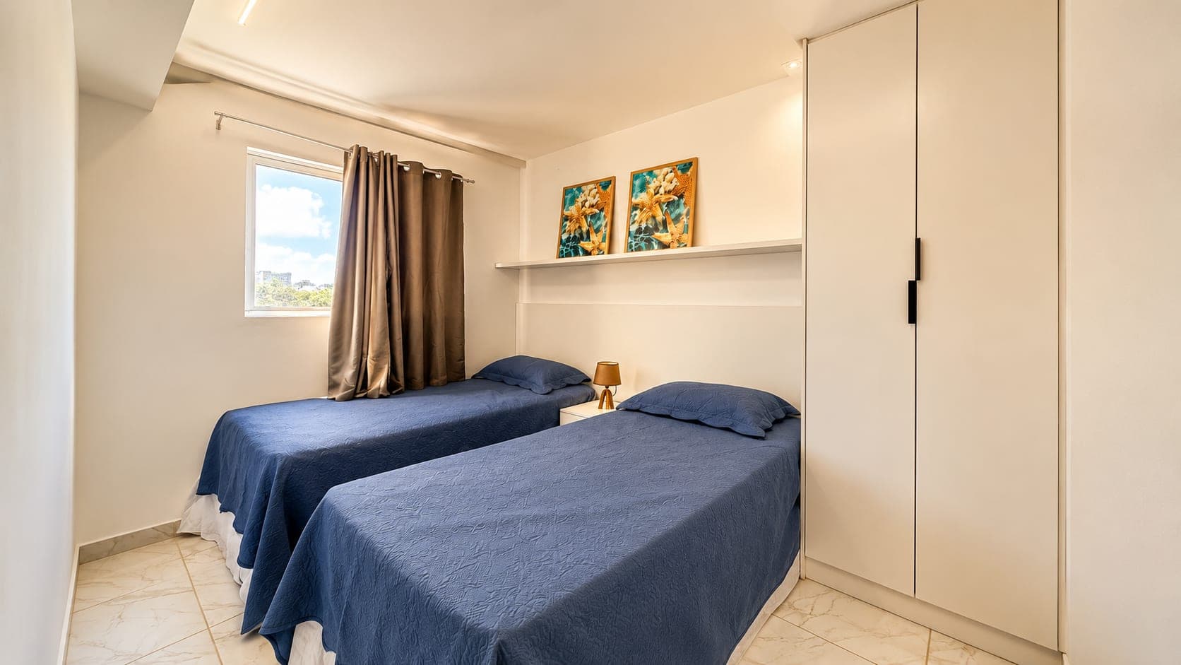 Quarto com duas camas, cortinas e armário planejado na unidade decorada do Visual Residence